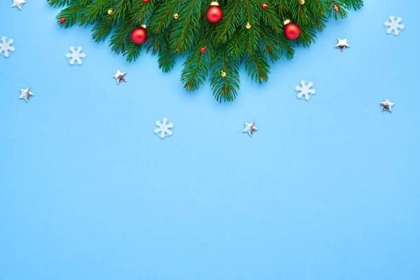 istock Christmas card. Branches of a Xmas tree folded in a triangle decorated with red balls and white snowflakes, bright stars on a blue festive background. Background for your text and design 1133984165