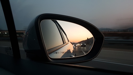 the sunset on the rearview mirror of a car. Daegu, South Korea. January, 27, 2018