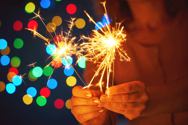 istock Holiday dynamic postcard. A happy boy holds a lighted fireworks on a blurred background of a bright Christmas garland. Meeting the new year. Christmas evening 1133986744