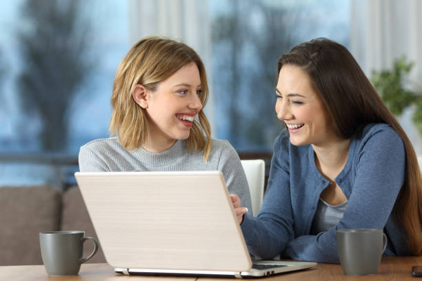 istock Happy friends using laptop and talking at home 1133987420