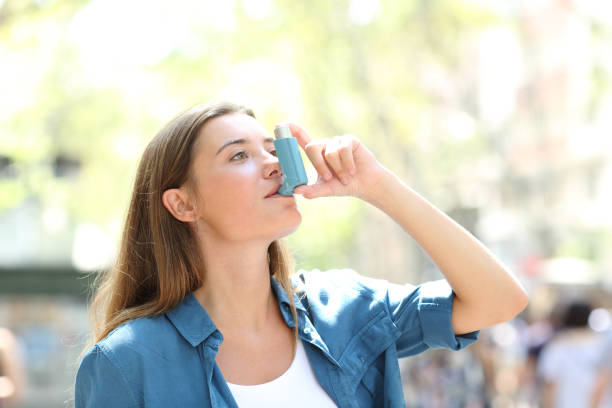 asthmatische frau mit inhalator auf der straße - asthmatisch stock-fotos und bilder