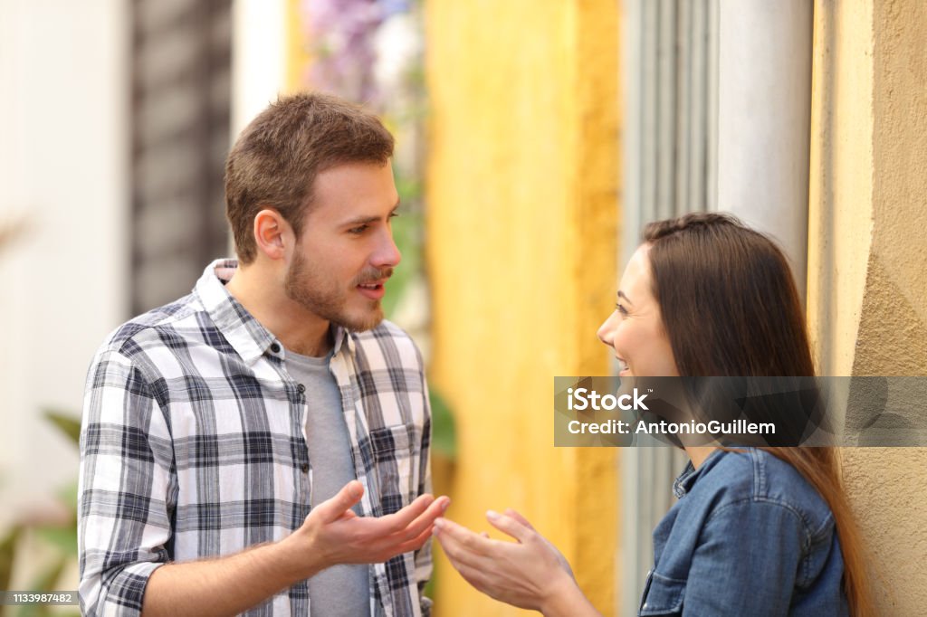 Couple talking standing in a colorful street Talking Stock Photo