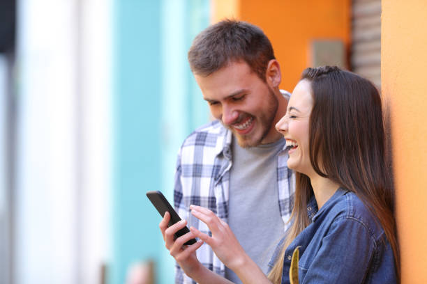 istock Happy couple laughing checking smart phone 1133987905