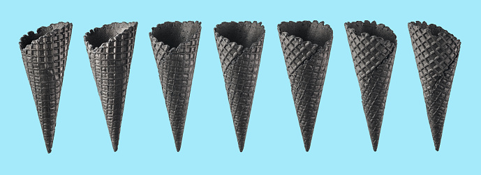 Various ice cream cones isolated on blue background. Various perspective of black waffle sugar cones on bright blue background
