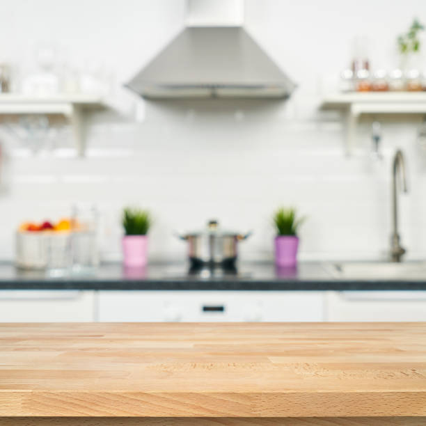 a wooden table top of the kitchen table on a blurry background of the kitchen interior. bright interior decoration of home cooking. bright ready-made picture for your individual design - domestic kitchen contemporary domestic room lifestyles imagens e fotografias de stock