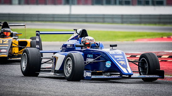 Men driving formula racing cars on motor racing track.