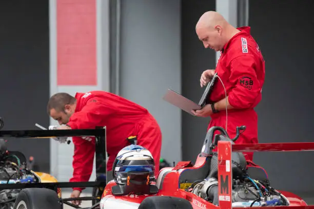 Pit crew member using laptop at pit stop.