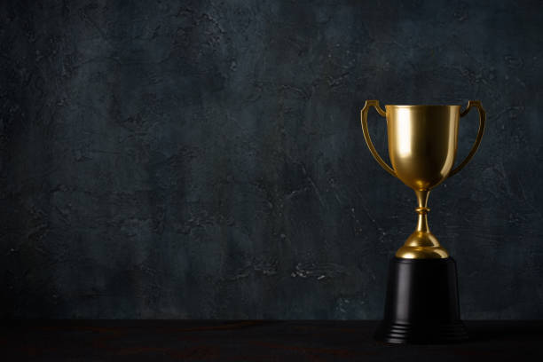 Golden trophy cup on table dark background stock photo