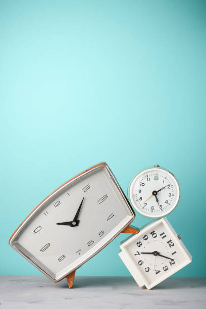 Retro alarm clocks tilted and stacked time concept on vintage blue background