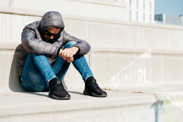 istock man curled up sitting on an outdoor stairway 1133996900