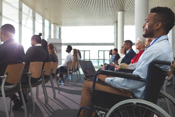 istock Disabled young businessman using laptop during seminar 1133997706