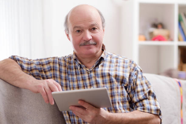 istock Senior man using tablet sitting at home. 1133999186