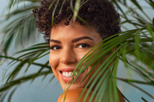 belleza jovencita sonriendo a través de hojas de palma - leaf epidermis fotografías e imágenes de stock