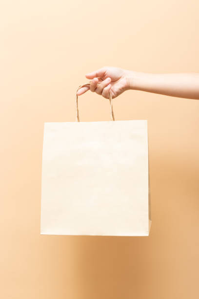 mão que prende um saco de papel isolado no fundo - green consumerism bag paper bag - fotografias e filmes do acervo