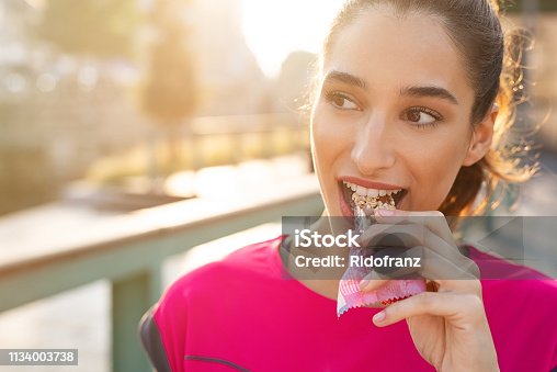 istock Sporty woman eating energy bar 1134003738