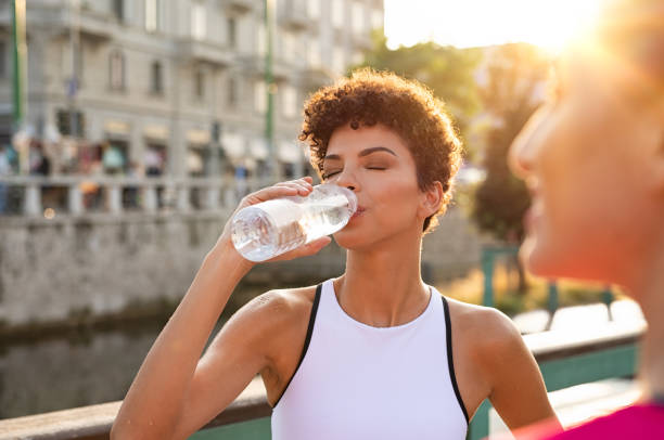 Athletic woman drinking water after workout