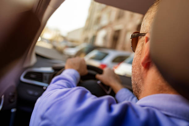 istock Man of style and status. Handsome young man in full suit smiling while driving a car 1134004930