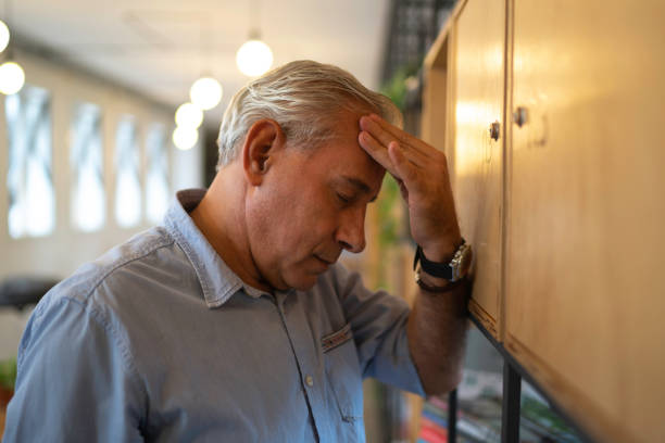 uomo d'affari senior frustrato con mal di testa sul lavoro - professional occupation firing people adversity foto e immagini stock