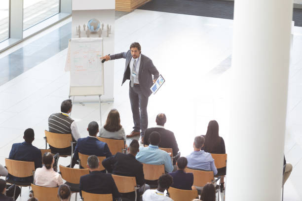 istock Businessman speaking and holding digital tablet and microphone while pointing at flip chart at confe 1134007245