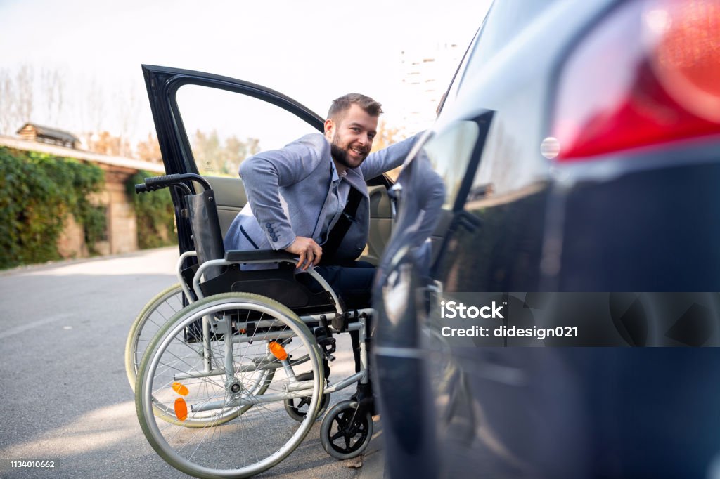 Handicapped man attempting to get in the car Handicapped man attempting to get in the car in the handicapped parking zone Car Stock Photo