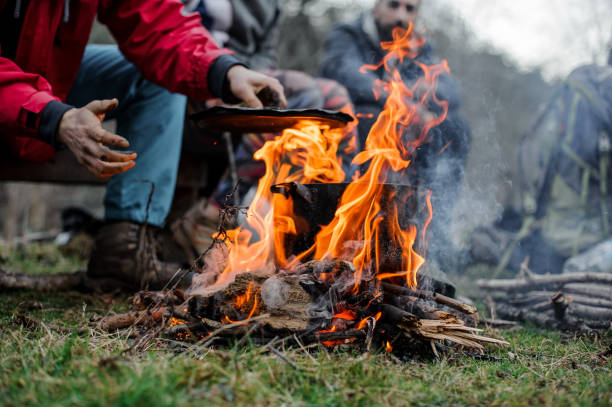 istock Boy in a red jacket placing a cover on the black pan standing on the bonfire 1134014539