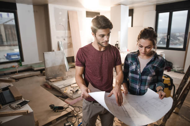 istock Young happy couple examining blueprints while being on construction site in their apartment. 1134015008
