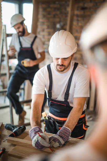 istock Young manual worker drawing measurements on a plank at construction site. 1134015589