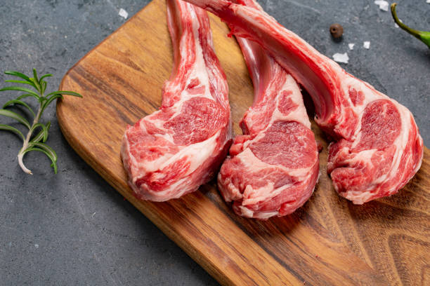 istock Raw meat on the bone with fresh herbs and spices, black background for cooking with copy space, top view. 1134015924