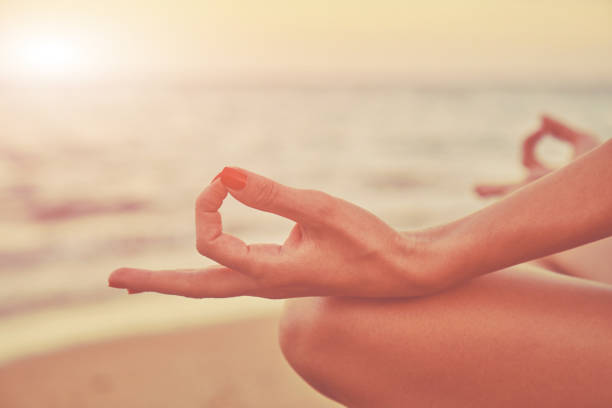 istock Young woman practicing yoga on the beach. Focus on hand. 1134017509