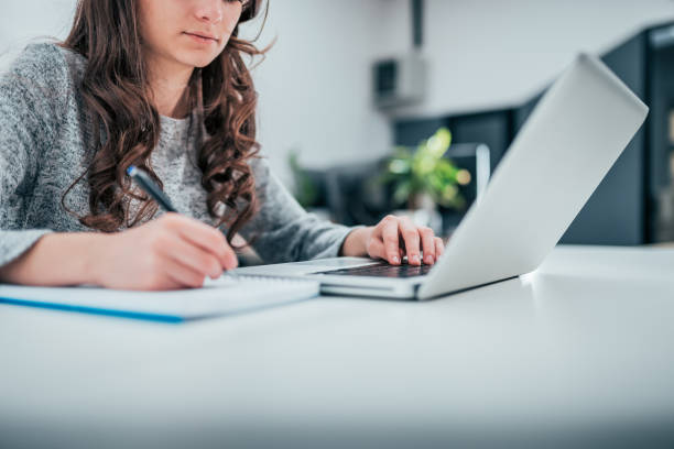 istock Low angle image of female person working on laptop and taking notes, copy space. 1134018487
