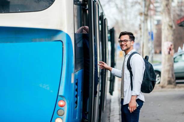 apuesto joven sonriente que se está metiendo en el autobús. - transporte público fotos fotografías e imágenes de stock