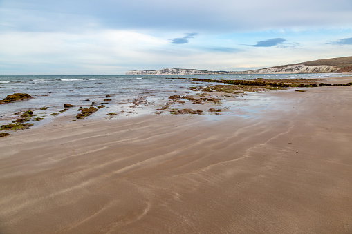 Looking out towards the chalk cliffs at Freshwater Bay, over Compton Bay beach during low tide