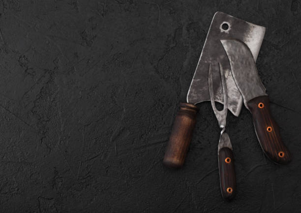 istock Vintage meat knife and fork and hatchet on black table background. Butcher utensils. Space for text 1134023904