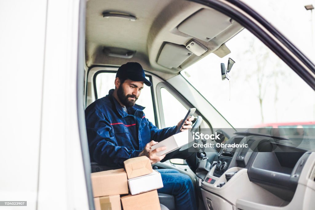 Delivery man with a parcel box in the car. Delivery Person Stock Photo