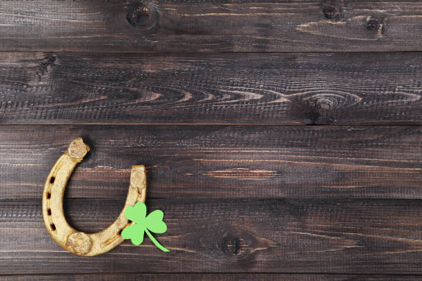 istock St.Patrick's Day. Golden horseshoe with clover leaf on wooden table 1134027616