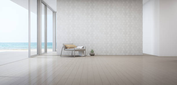 木製の床のドアの近くにアームチェア付きの豪華なビーチハウスのシービューリビングルーム。休暇の家や休日のヴィラで空の白い三角形のパターンの壁の背景。 - wall office indoors white ストックフォトと画像