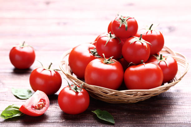 istock Fresh and ripe tomatoes with basil leafs on brown wooden table 1134029568
