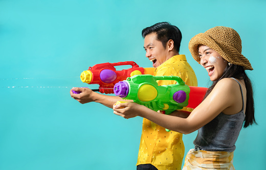 Asian people are using water guns play in the Songkran festival. Studio concept