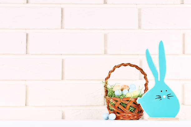 istock Wooden rabbit with easter eggs in basket on brick wall background 1134035477