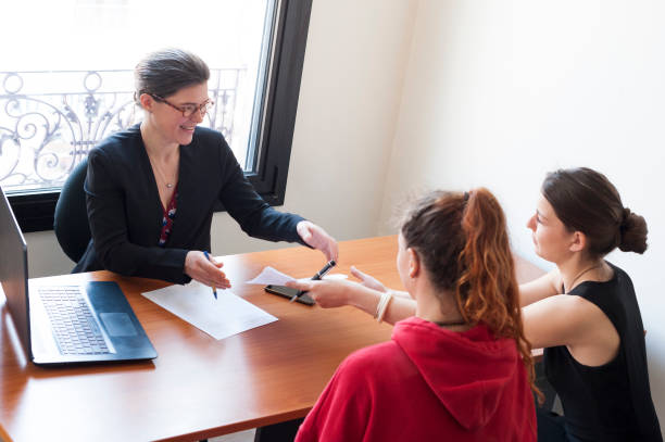 deux jeunes femmes signent un contrat - lawyer family talking discussion photos et images de collection