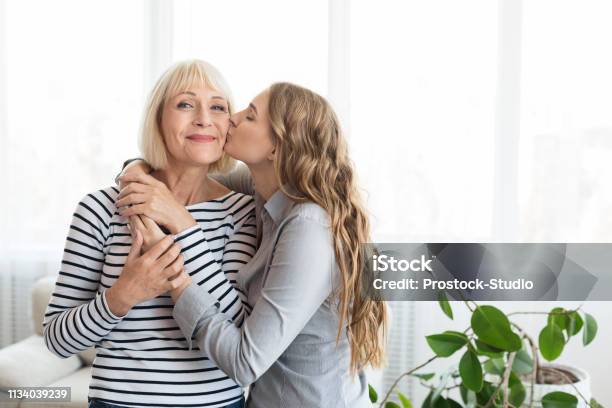Woman Kissing Senior Mother On The Cheek Stock Photo - Download Image Now - Mother, Daughter, Senior Adult