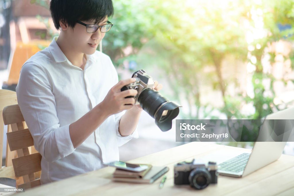 glans Knop Marine Young Asian Man Holding Digital Singlelens Reflex Camera Checking Photo On  Camera Screen Display Sitting With Laptop Computer And Smartphone On The  Table Photography Art And Hobby Concepts Stock Photo - Download