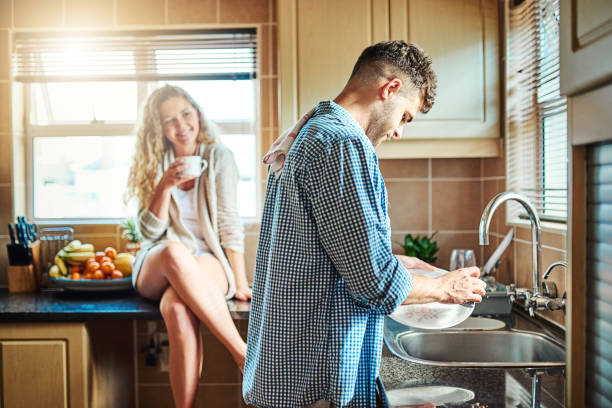 Cleaning up after breakfast Shot of a woman keeping her husband company while he does the dishes washing dishes photos stock pictures, royalty-free photos & images
