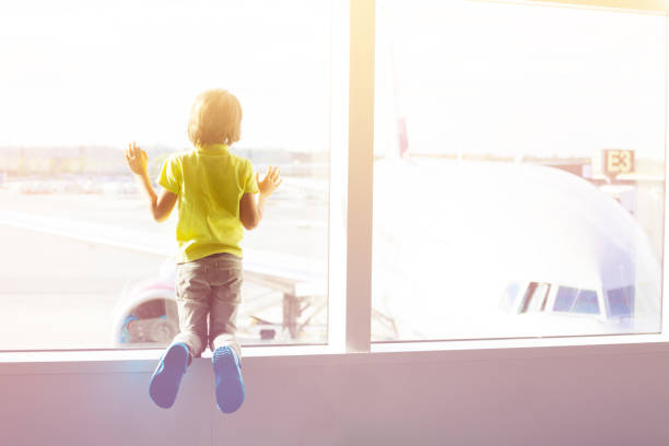 istock Boy looks on aircrafts through window of terminal 1134041413