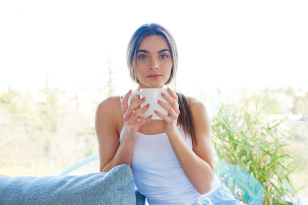 istock Beautiful young woman holding mug in her hand while relaxing on sofa at home 1134045406