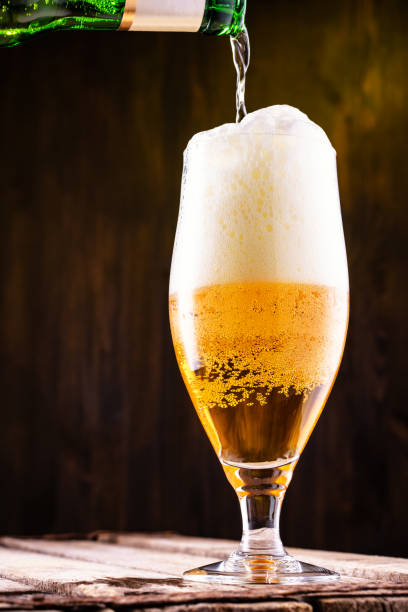 istock Cold beer is pouring into a glass forming foam. 1134051817