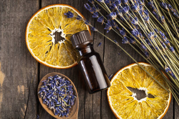 aceite esencial de lavanda y naranja seco sobre una mesa de madera, vista superior - aromaterapia fotografías e imágenes de stock