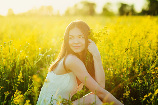 Beautiful caucasian brunette girl the flowers field in summer sunset Healthy Lifestyle