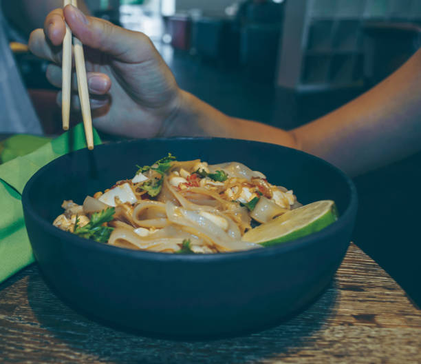 woman holding chopsticks and going to eat asian noodles meal