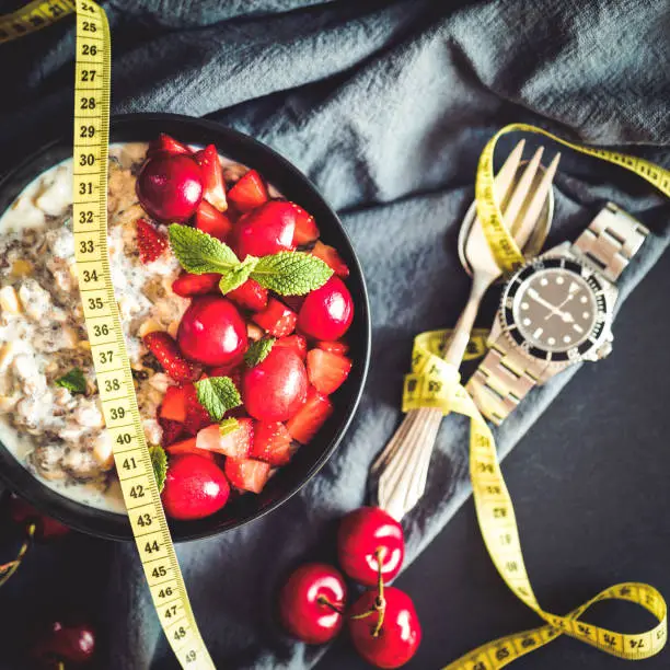 Losing weight with intermittent fasting gets more and more popular, here showed with a clock and a delicious vegan porridge